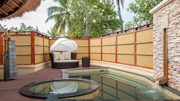 A spa area with a hot tub, a seating area, and a pool.