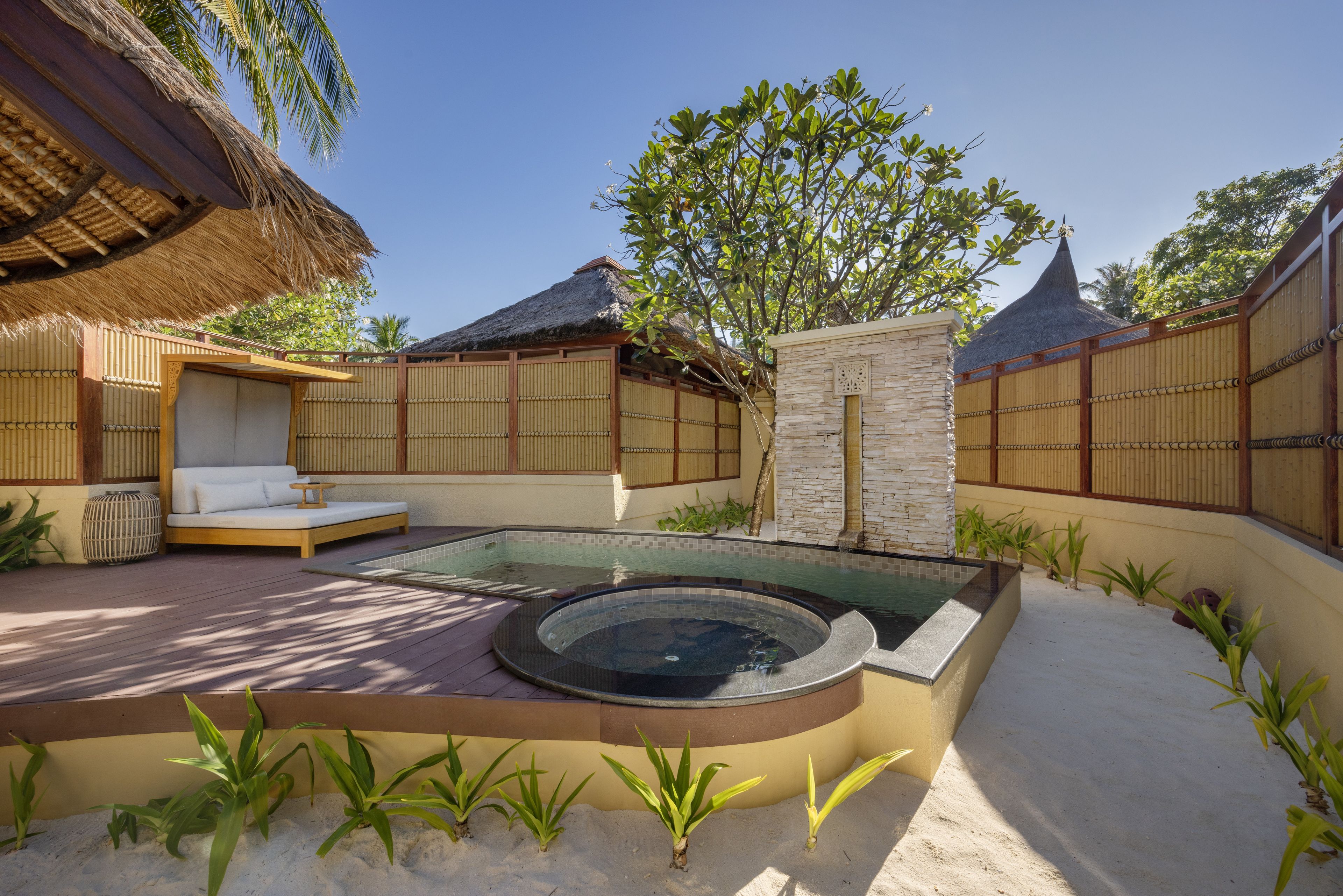 Un área de spa con bañera de hidromasaje, asientos y piscina.