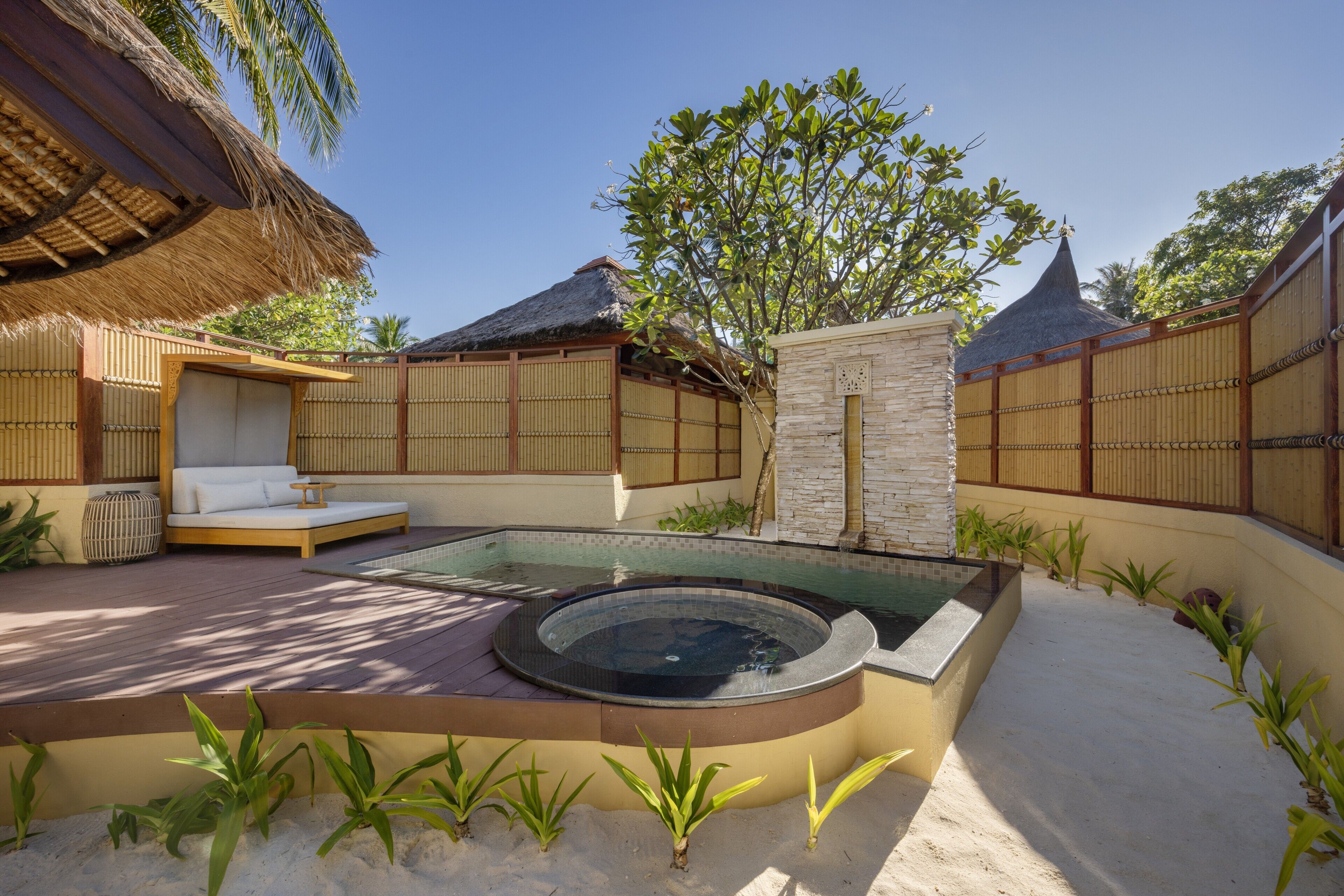A spa area with a hot tub, seating, and a pool.