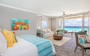 A hotel room with a bed, a sofa, a coffee table, and a view of the ocean.