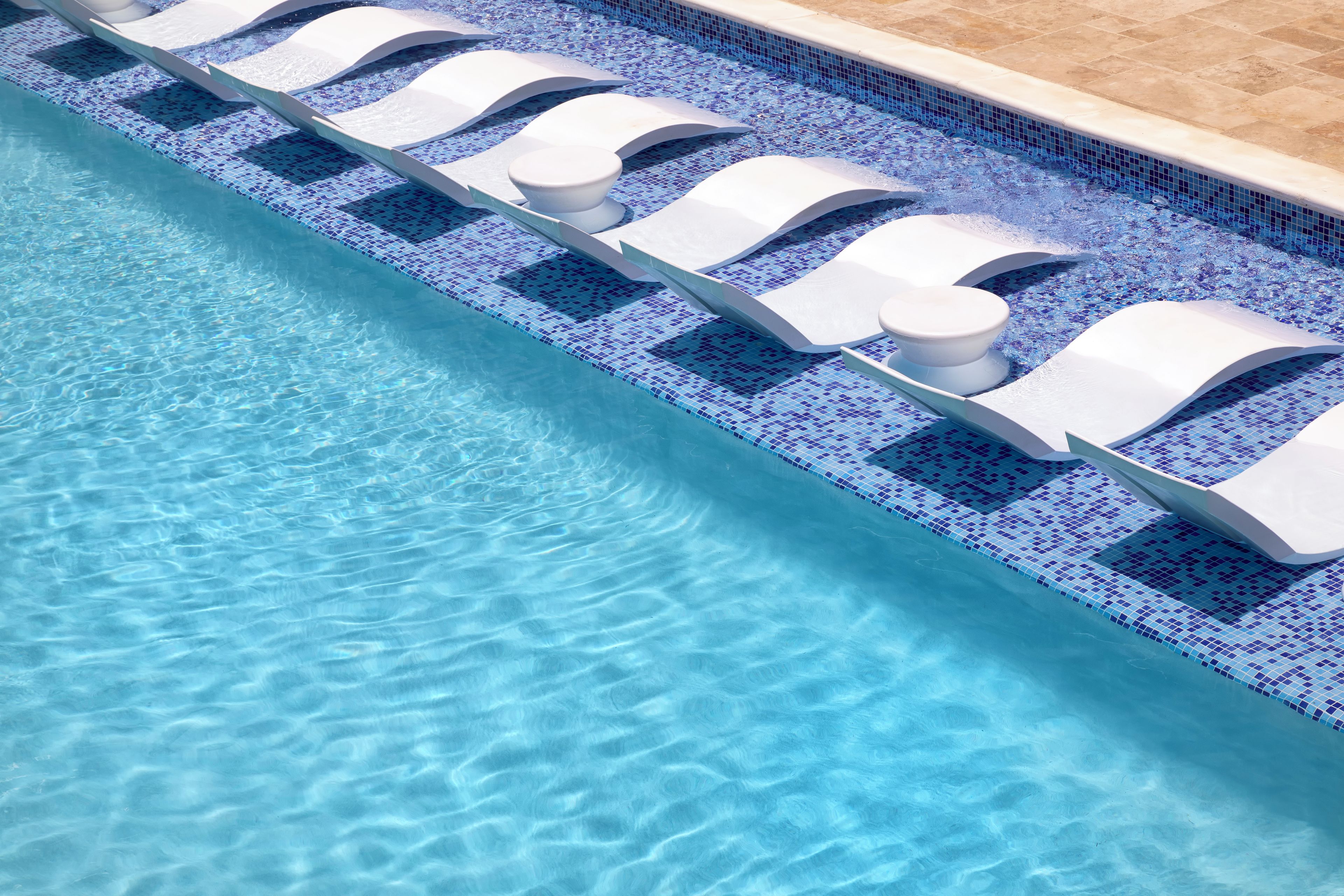 A swimming pool with clear blue water and a tiled edge.