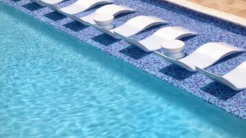 A swimming pool with clear blue water and a tiled edge.