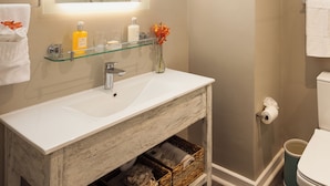 A bathroom with a glass shelf vanity, a mirror, a shower, and a toilet. - Sea Breeze Beach House All Inclusive by Ocean Htls (CHRIST CHURCH)