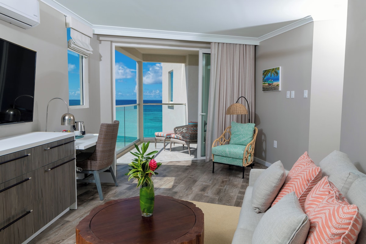 A modern living room with a view of the ocean, a dining area with a view, and a kitchen with a large window.