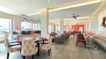 A spacious restaurant with high ceilings, modern lighting, and a mix of seating arrangements including tables and sofas.