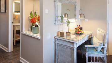 A well-lit hallway with a mirror, a vase of flowers, and a chair with a patterned cushion.