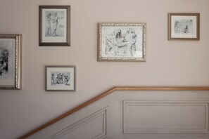 Een muur met vijf ingelijste kunstwerken.
