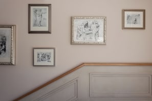 Una pared con cinco obras de arte enmarcadas.