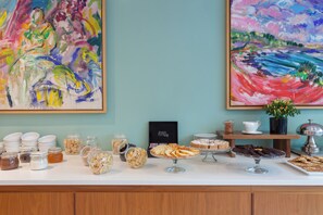 Una taula de buffet amb diversos plats i una selecció de quadres a la paret.