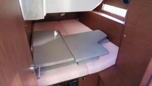 Un interior compacte amb un llit, un petit panell de control i una finestra.