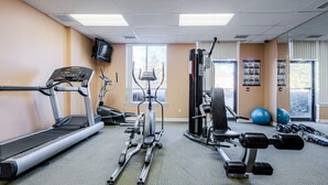 A gym with treadmills, an elliptical, a weight bench, and free weights.