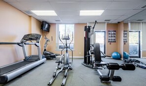 A gym with treadmills, an elliptical, a weight bench, and free weights.