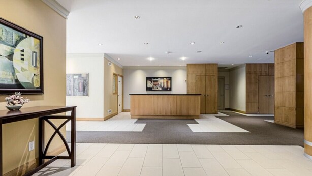 A spacious lobby with a reception desk, a wooden reception area, and a large artwork on the wall.
