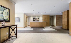 A spacious lobby with a reception desk, a wooden reception area, and a large artwork on the wall. - Stylish 1BR+Den Retreat in Markham (Markham)