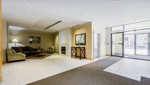 A hotel lobby with a seating area, a fireplace, and a large glass door leading outside.