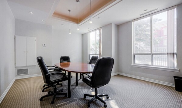 A conference room with a round table, four chairs, and large windows.