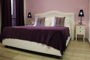A bedroom with a bed, two bedside tables, and a window with curtains.