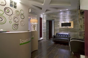 A reception area with a reception desk, a sofa, and a wall-mounted TV.