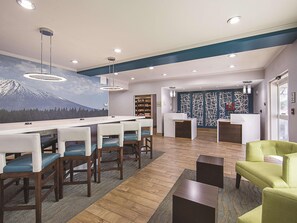 A modern reception area with a bar, seating, and a mountain mural. - La Quinta Inn Suites Central Point Medford (Central Point)