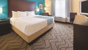 A hotel room with a large bed, a desk, a chair, a television, and a window with curtains. - La Quinta Inn Suites Central Point Medford (Central Point)