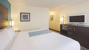 A hotel room with a bed, a television, a desk with a computer, and two framed pictures on the wall. - La Quinta Inn Suites Central Point Medford (Central Point)