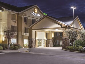 A hotel entrance with a clear sign, a covered driveway, and a street lamp. - La Quinta Inn Suites Central Point Medford (Central Point)