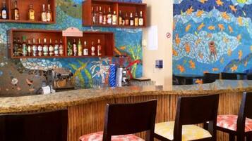 A bar area with a mosaic wall, shelves of bottles, and a coffee machine.