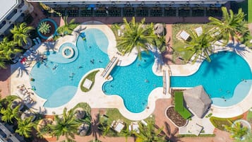 Eine Luftaufnahme eines Resorts mit mehreren Schwimmbecken, Palmen und Liegebereichen.