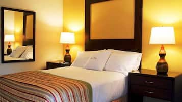 A hotel room with a bed, two bedside lamps, a nightstand, a mirror, and a headboard.