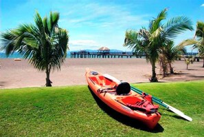 A boat on a grassy area with a beach and palm trees in the background.