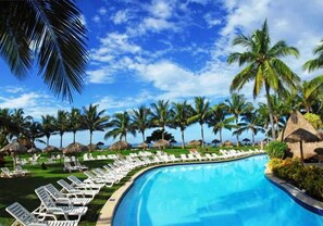 A poolside area with lounge chairs and palm trees.