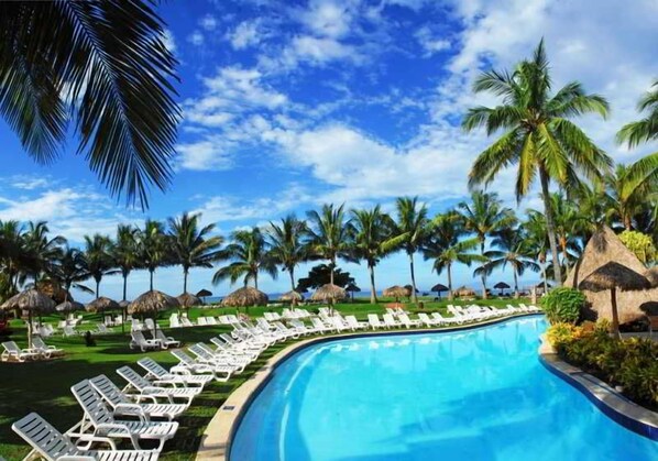 A poolside area with lounge chairs and palm trees. - Fiesta Resort All Inclusive (El Roble)