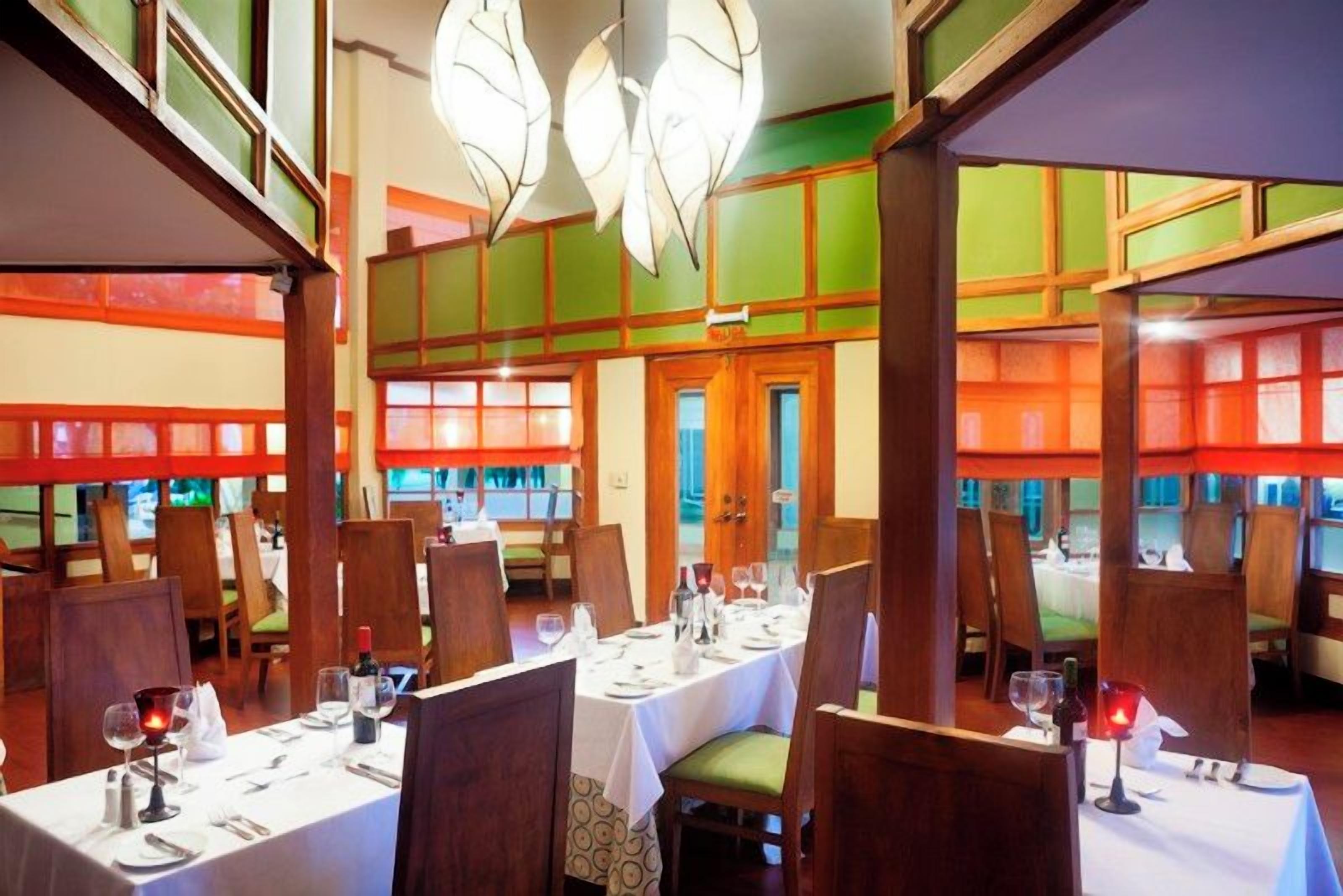 A restaurant with multiple dining tables, chairs, and a view of the outside through large windows.