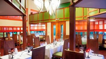 A restaurant with multiple dining tables, chairs, and a view of the outside through large windows.