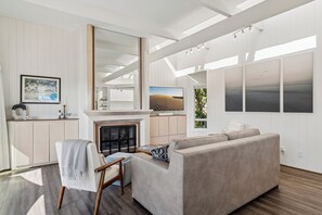 A modern living room with a fireplace, a sofa, a chair, and artwork on the walls. - Stunning Ocean-View Home in the Heart of Laguna Beach! Walk to Beach! (Laguna Beach)