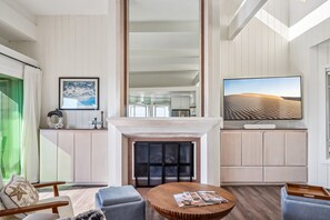Een moderne woonkamer met een open haard, een zithoek en een grote flatscreen-televisie.