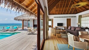 A spacious room with a wooden ceiling, a pool, and a view of the ocean.