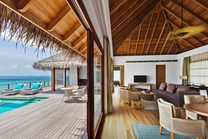 A spacious room with a wooden ceiling, a pool, and a view of the ocean.