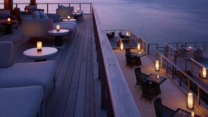 A wooden deck with seating and tables, overlooking the sea.
