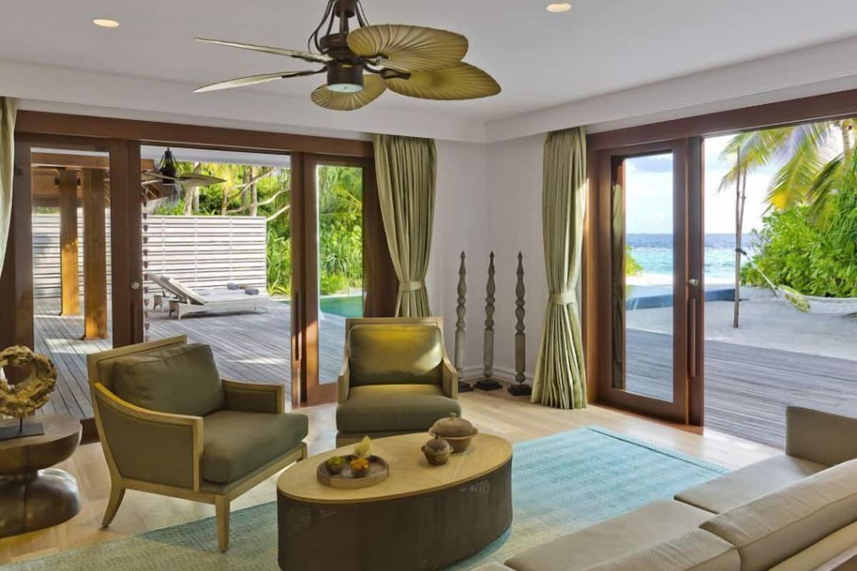 A modern living room with a view of the ocean, a ceiling fan, and a round coffee table.