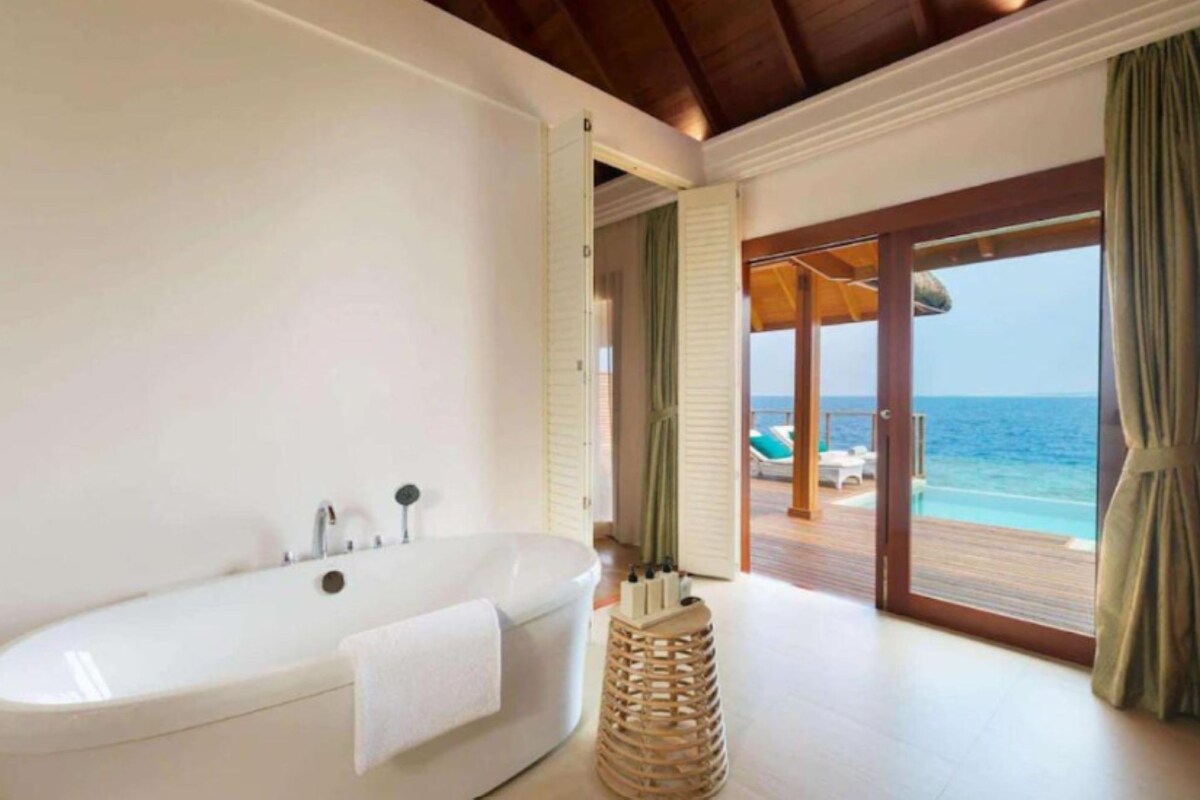 A bathroom with a bathtub, a towel, and a wooden stool.