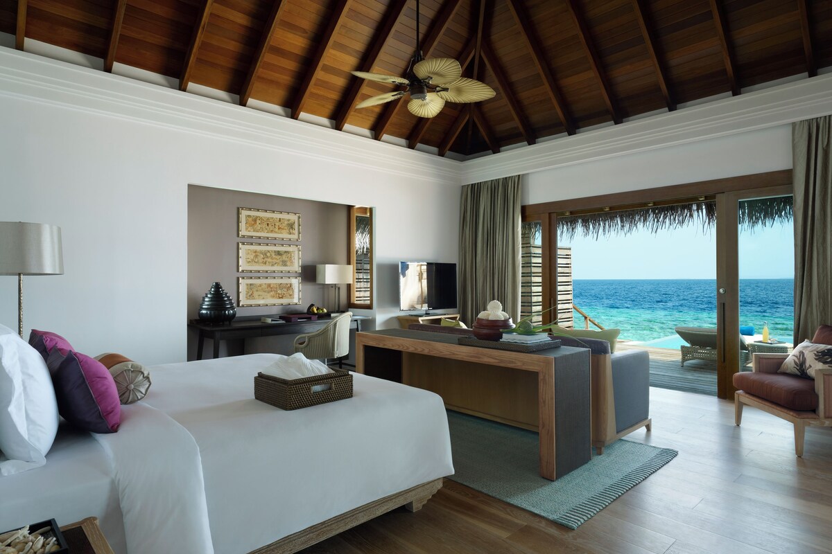 A hotel room with a bed, desk, and a view of the ocean.