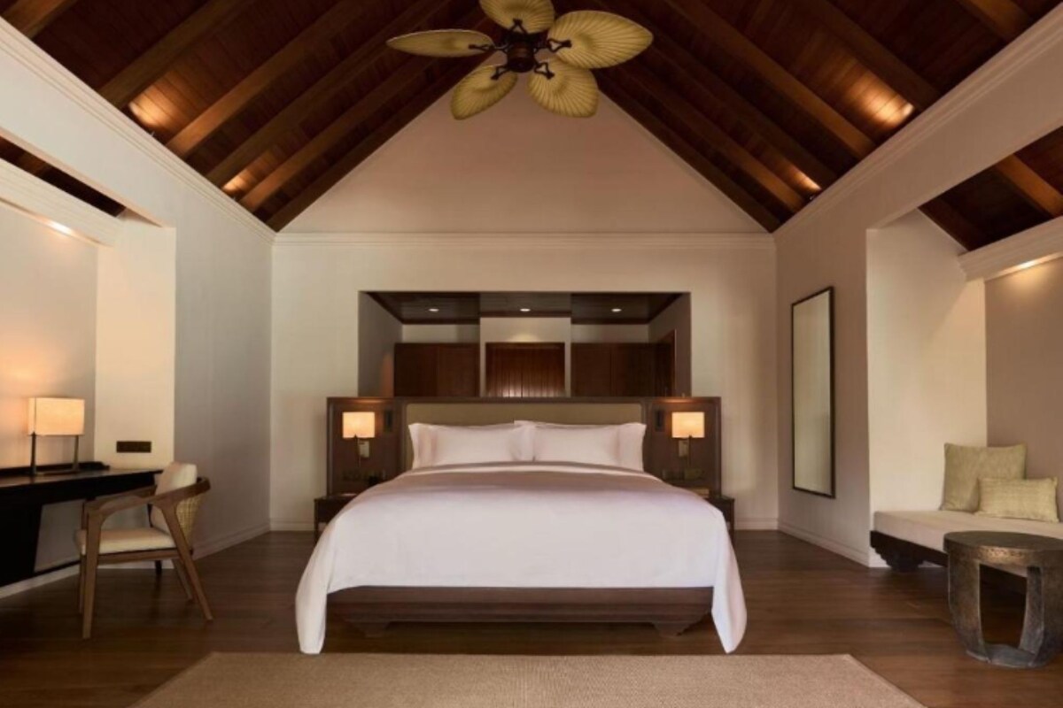 A bedroom with a large bed, a desk, and a chair.