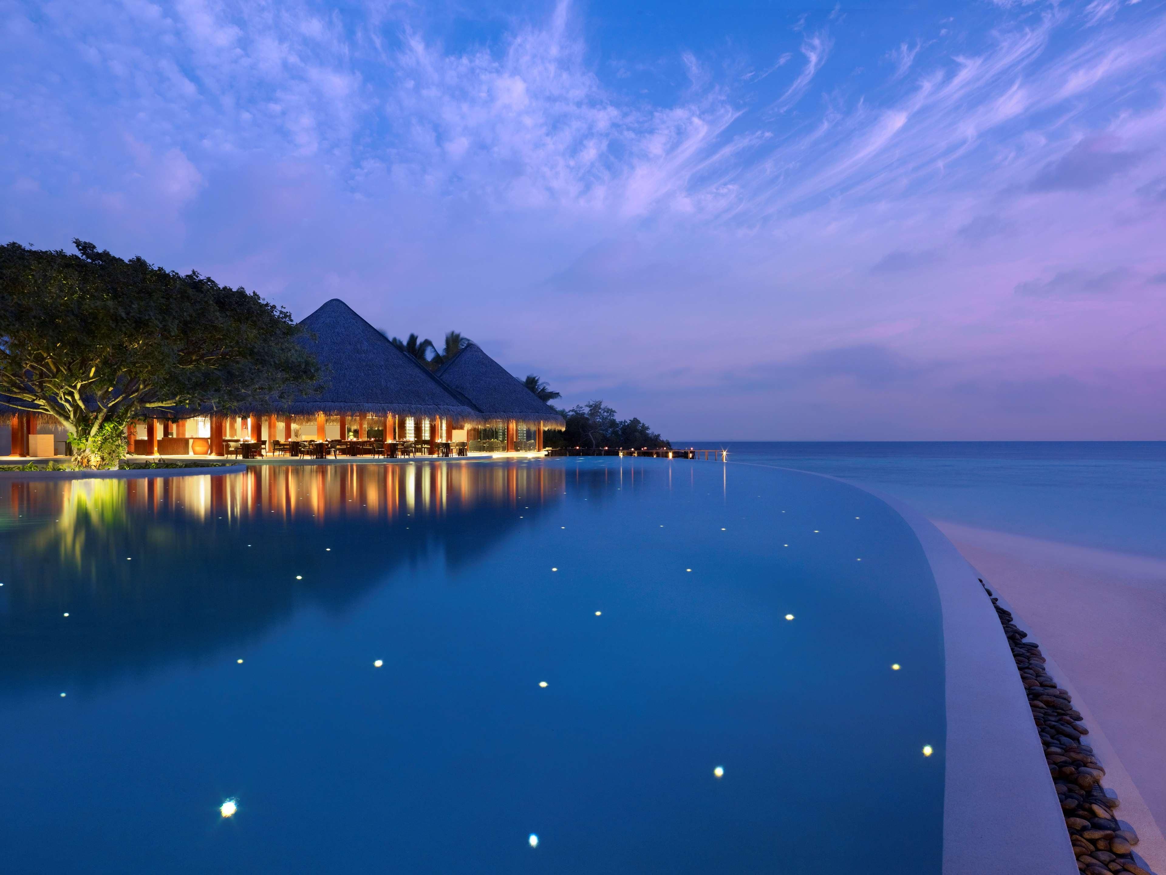 A resort with overwater bungalows, a swimming pool, and a beach.