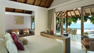 A bedroom with a large bed, a desk, and a view of a beach.