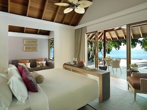 A bedroom with a large bed, a desk, and a view of a beach.
