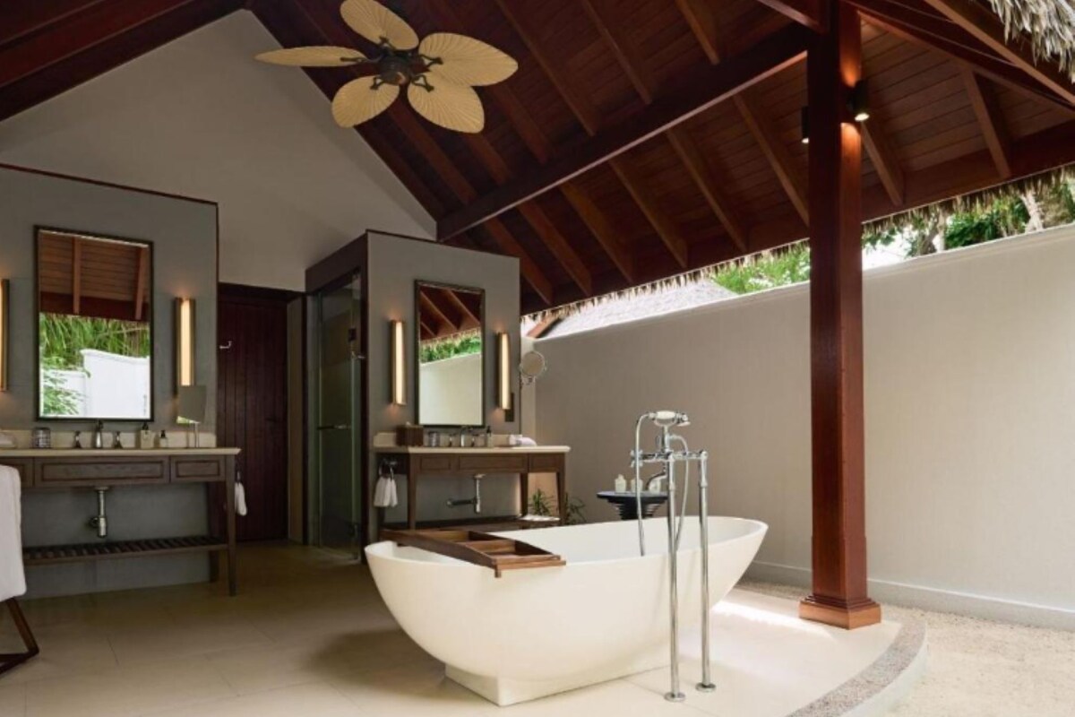 A modern bathroom with a freestanding bathtub, a vanity with a mirror, and a ceiling fan.