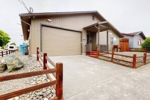 A residential garage with a closed garage door, a wooden fence, and a gravel driveway. - Entire Duplex Oasis/ 4BR, 4BA, Garages, Sleeps 12 (Eureka)