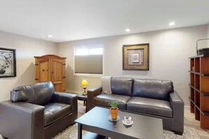 A living room with a sofa, a coffee table, a lamp, and a bookshelf. - Entire Duplex Oasis/ 4BR, 4BA, Garages, Sleeps 12 (Eureka)