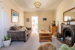 A cozy living room with a sofa, a coffee table, a fireplace, and a mirror. - Kirkmay Road (No 18)  Mayfield House | Crail (Crail)